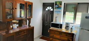 Kitchen area with a refrigerator, microwave, toaster, and wooden cabinet with glass doors.