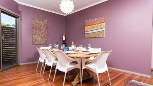 Un comedor con una mesa redonda, sillas blancas y paredes moradas.