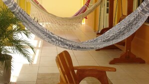 A hammock suspended between wooden chairs in a room with yellow walls and tiled flooring. - L'AMARELA MANSION 11 SUITES 50 BEDS NEIGHBORHOOD TO BEACH PARK (AQUIRAZ)