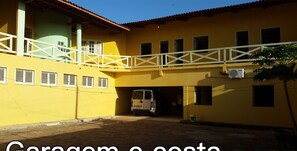 Un bâtiment jaune doté d’un espace de stationnement couvert, dans lequel est garé un fourgon blanc.