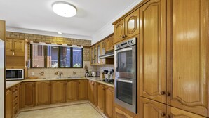 Una cocina con armarios de madera, microondas, estufa y ventana con vistas al exterior.