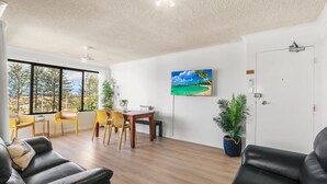 Una sala de estar moderna con comedor, ventanas amplias, televisor de pantalla plana y una puerta con picaporte.