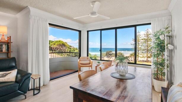 Una habitación amplia con una gran mesa de madera, un sofá cómodo y vista a la playa.