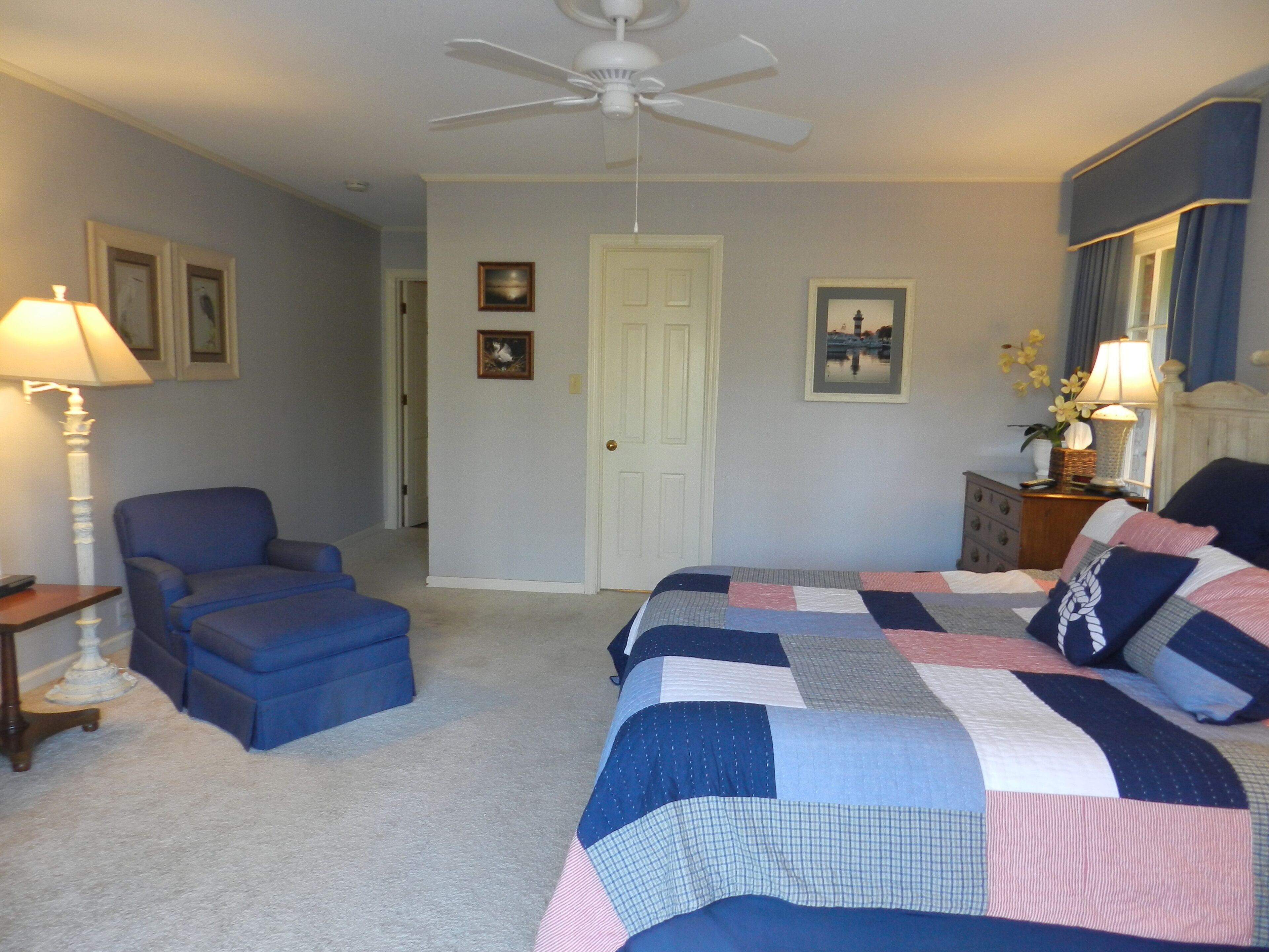 A bedroom with a bed, a chair, a desk, and a ceiling fan.