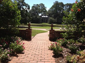 Stroll through the beautifully landscaped garden, lined with vibrant greenery and flowering plants, to the classic building in the distance.
