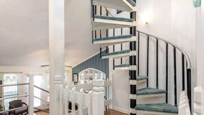 A modern interior with a spiral staircase, wooden flooring, and a white railing.