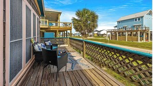 A wooden deck with outdoor furniture, a view of a residential area, and a clear blue sky.