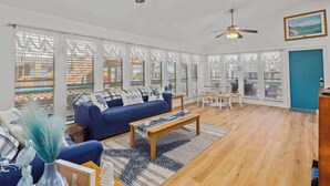 A spacious living room with a blue sofa, wooden coffee table, and a dining area with white chairs.
