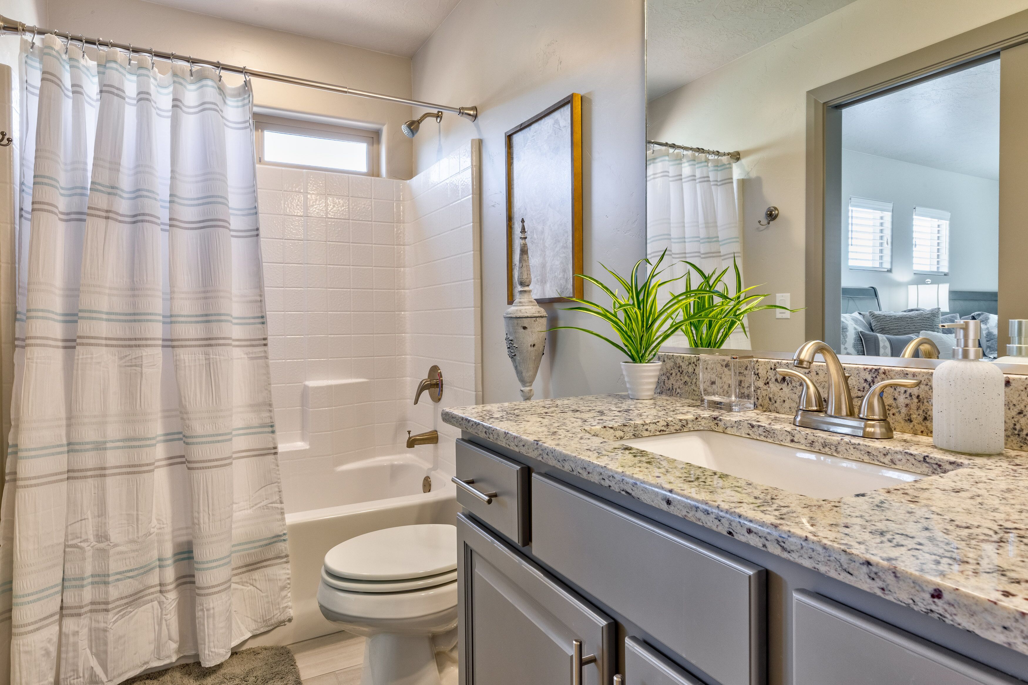 A bathroom with a shower, toilet, sink, and a mirror.