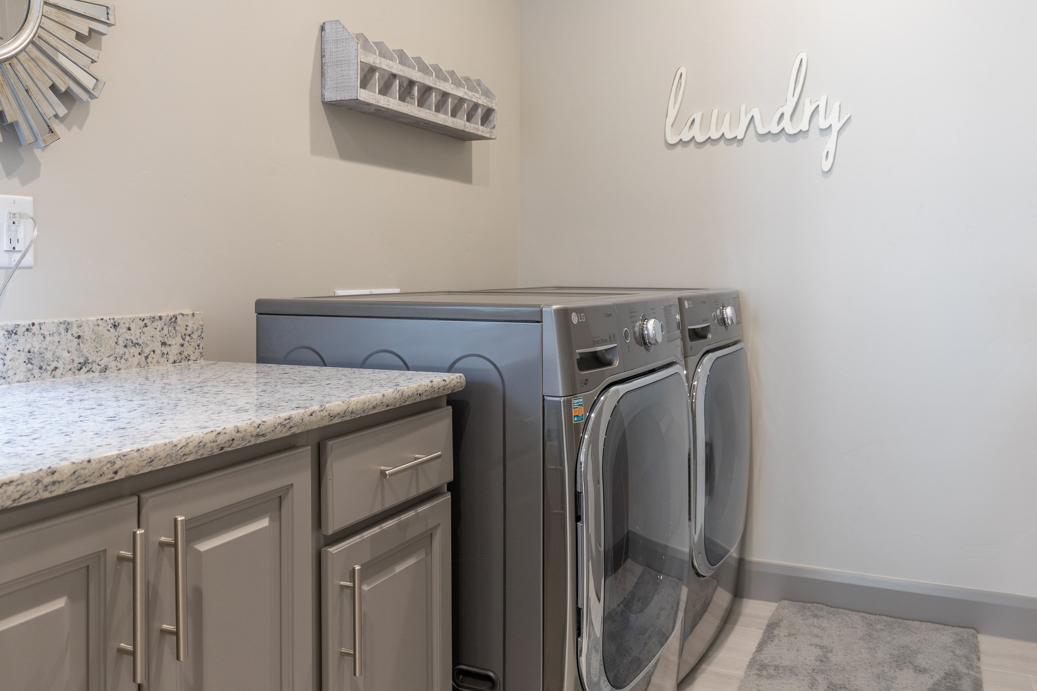A compact laundry room with a built-in washer and dryer, a granite countertop, and a 'laundry' sign on the wall.