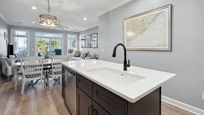 A modern kitchen with a large island, dark cabinetry, and a map on the wall. - Turtle Bay 21 - Riverview Condo - Pool (Folly Beach)