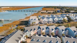 A coastal residential area with houses near a water body, a bridge, and a lighthouse in the distance. - Turtle Bay 21 - Riverview Condo - Pool (Folly Beach)