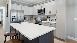 A modern kitchen with white cabinets, stainless steel appliances, and a large island. - Turtle Bay 21 - Riverview Condo - Pool (Folly Beach)