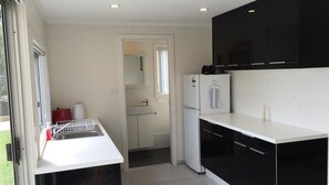 A modern kitchen with a white countertop, black cabinets, a refrigerator, and a sink. - SeaEsta - Waterfront - Jervis Bay  - 5 minutes to Hyams Beach (Erowal Bay)