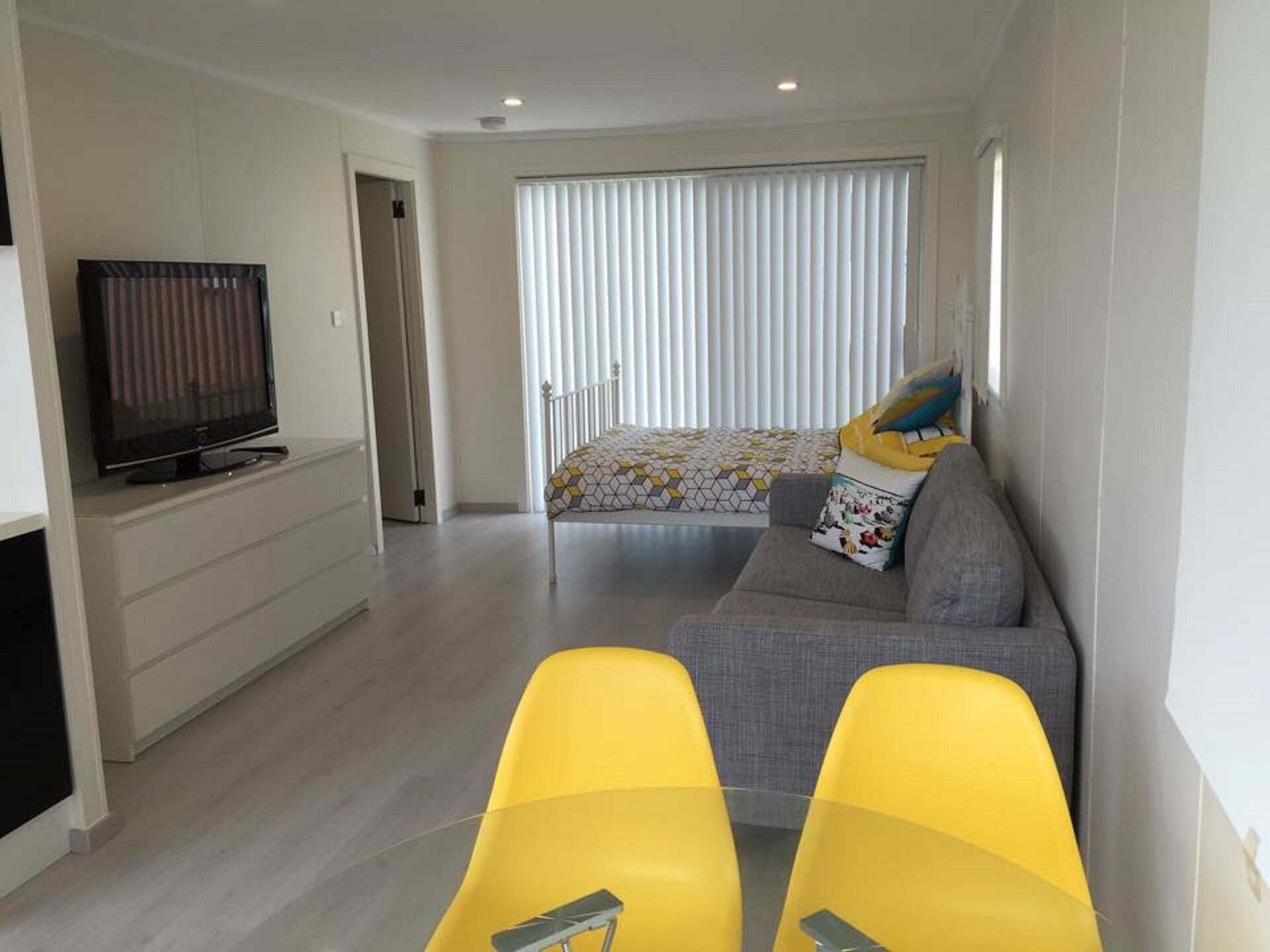 A modern bedroom with a bed, a TV, and a sofa.