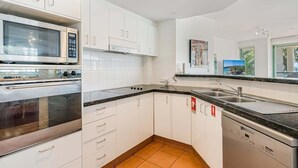 Een moderne keuken met witte kastjes, een magnetron, oven en vaatwasser.