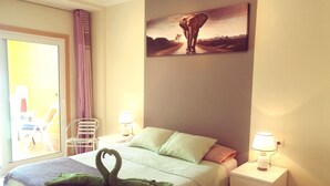 Een slaapkamer met een bed, twee nachtkastjes, een stoel, een raam met gordijnen en een schilderij aan de muur.