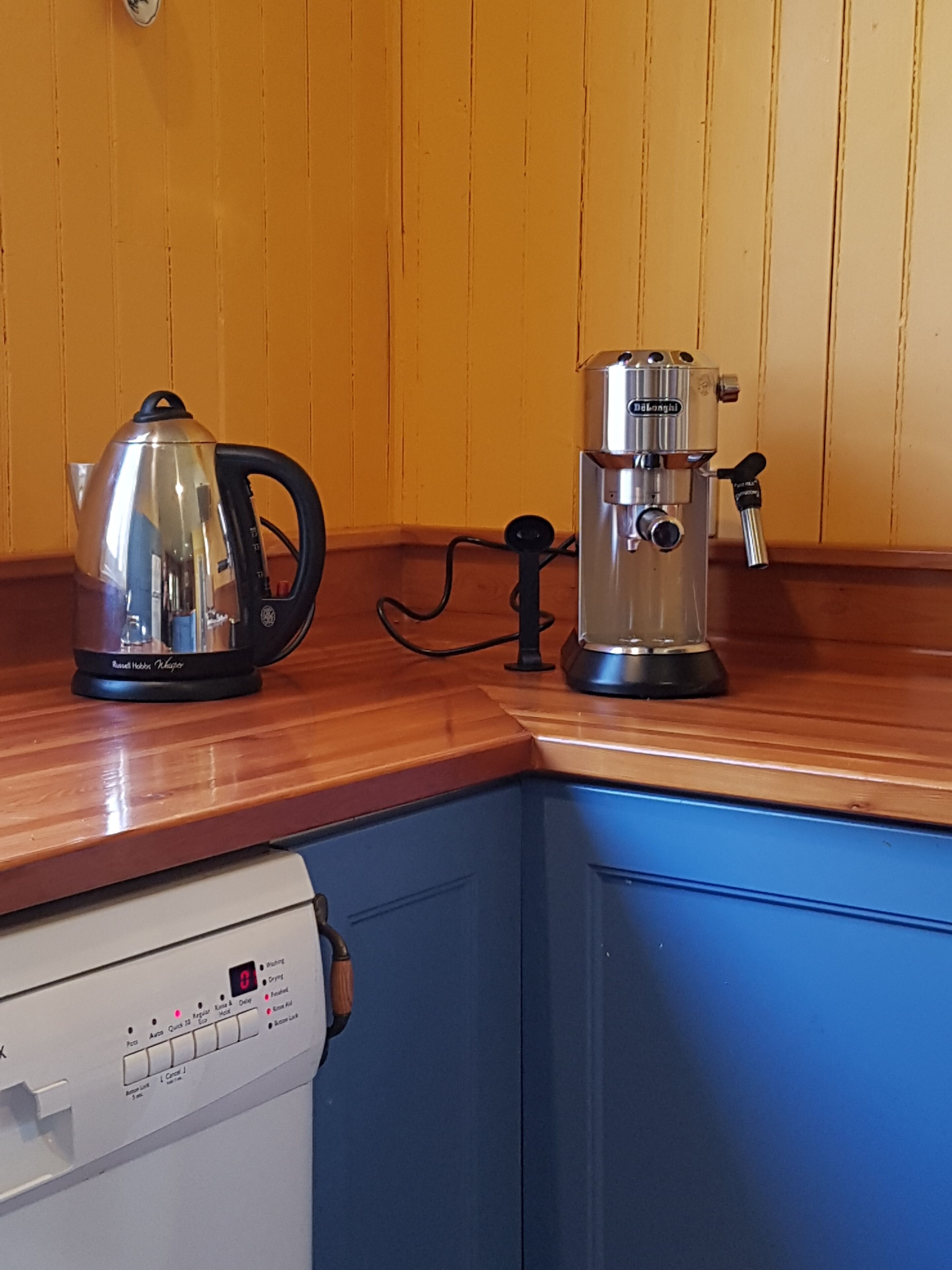 Eine Küche mit Wasserkocher, Kaffeemaschine und Geschirrspüler.