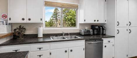 A kitchen with white cabinets, a stainless steel dishwasher, a toaster, and a coffee maker.