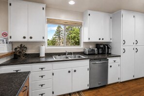 A kitchen with white cabinets, a stainless steel dishwasher, a toaster, and a coffee maker.