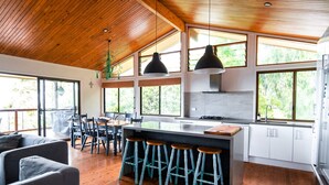 A modern kitchen with a central island, bar stools, and large windows. - Pets Allowed - This large family beach house also has great ocean and... (Point Lookout)