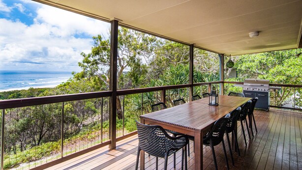 A covered outdoor dining area with a view of the ocean and surrounding greenery. - Pets Allowed - This large family beach house also has great ocean and... (Point Lookout)
