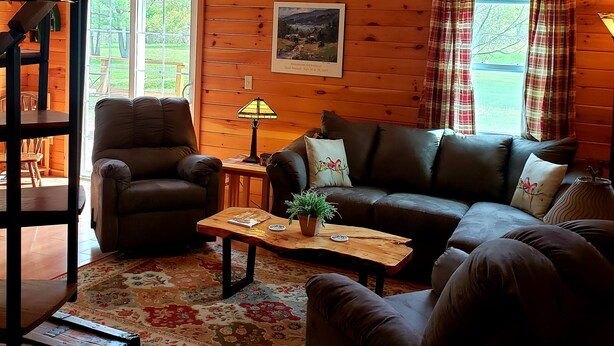 Ein gemütliches Blockhaus-Interieur mit Ledersofa, Couchtisch aus Holz und Kamin.