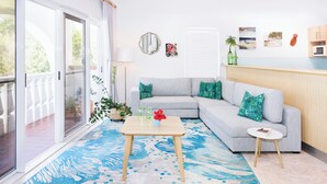 Ein Wohnzimmer mit einem grauen Sofa, einem kleinen runden Tisch und einem blauen Teppich mit Muster.