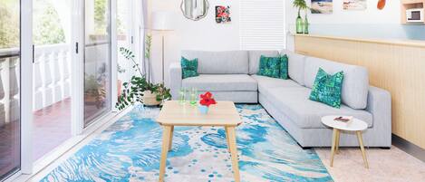 A living room with a grey sofa, a small round table, and a blue patterned rug.