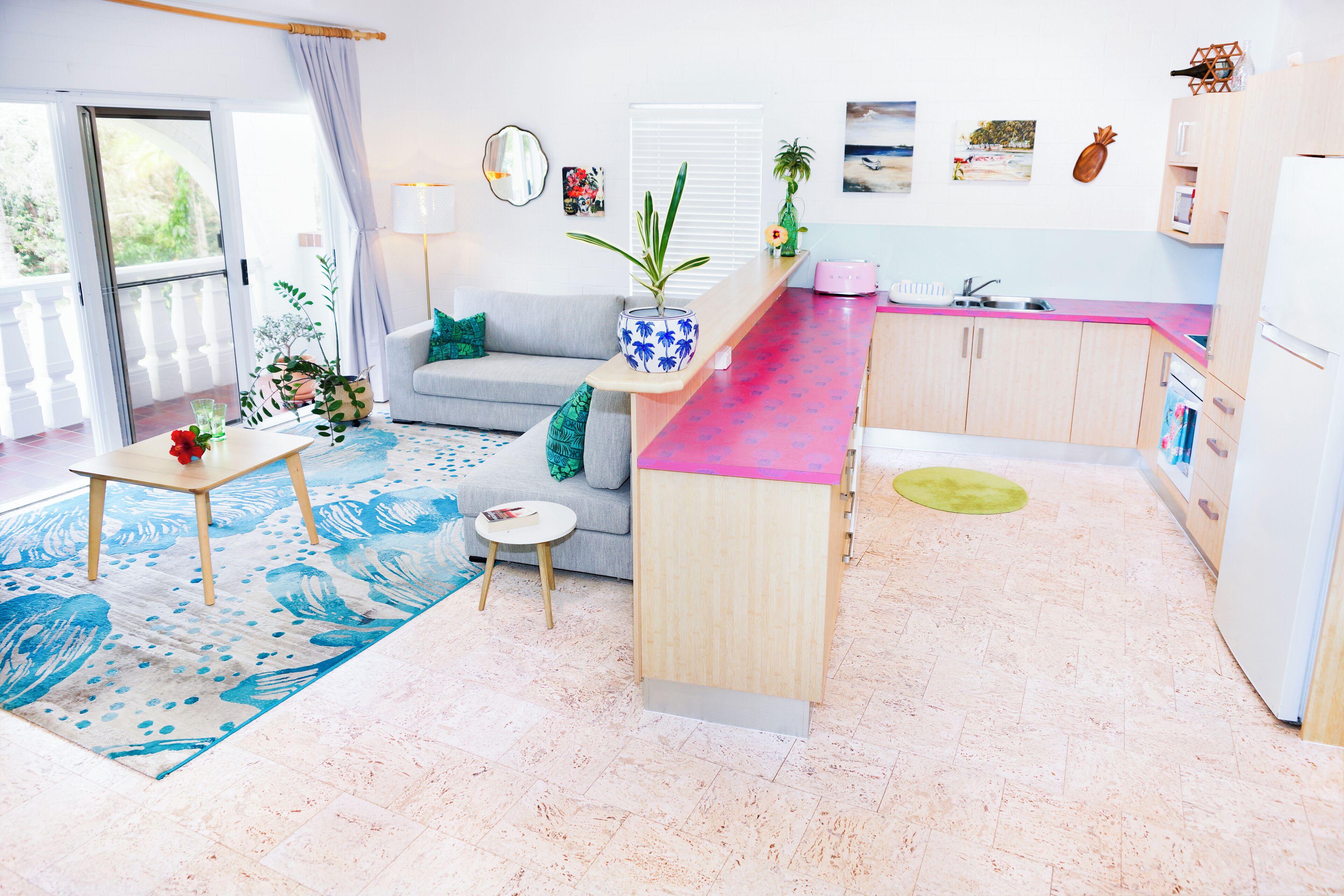 A modern kitchen with a pink countertop, wooden cabinets, and a built-in sink.