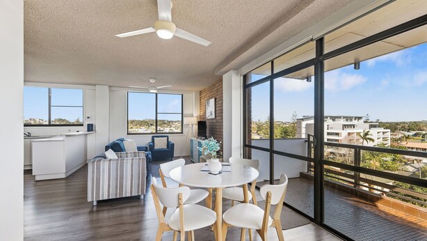 Un salón moderno con comedor, ventanas grandes y vistas a la ciudad.