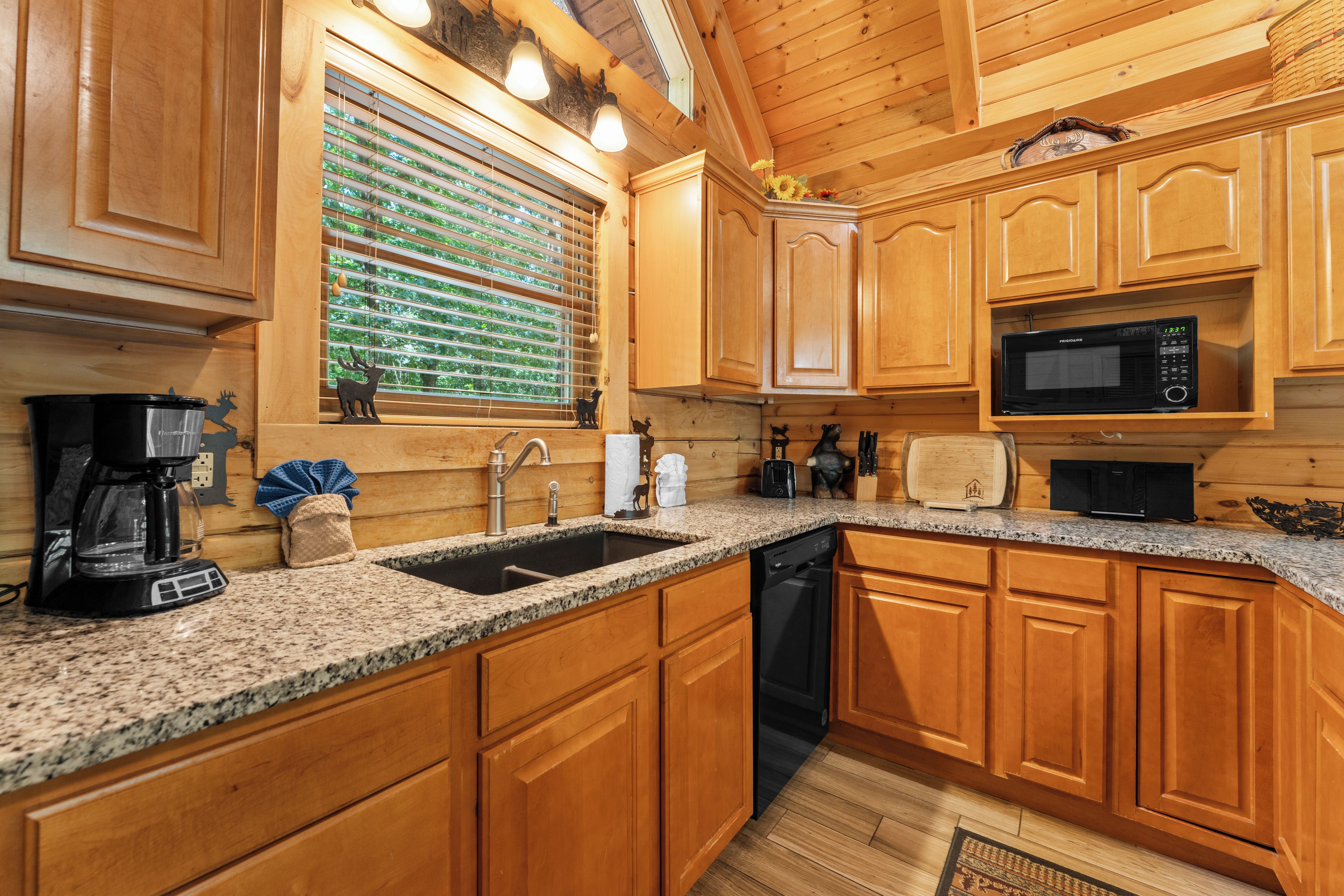 A kitchen with wooden cabinets, a granite countertop, a built-in microwave, and a coffee maker.