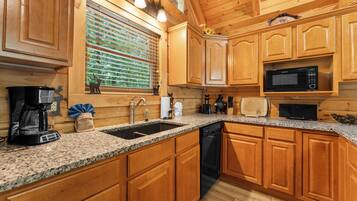 A kitchen with wooden cabinets, a granite countertop, a built-in microwave, and a coffee maker.