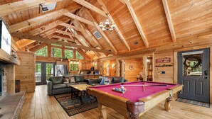 A spacious wooden interior with a pool table, leather sofas, and a fireplace. - Luxury Log Cabin Near Thunder Ridge_Pvt Fenced Yard & HotTub_Billiards_EV Car Charger_Free Tickets (Ridgedale)