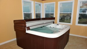 Ein Whirlpool in einem Raum mit beigen Wänden und großen Fenstern.