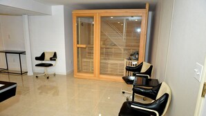 Ein Zimmer mit einer Schiebetür und einem Balkon, einem schwarzen Ledersessel, einem kleinen Tisch und einem weißen Stuhl.