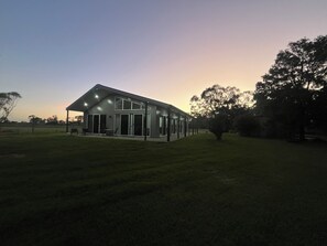 Uma casa moderna com um amplo pátio, grandes janelas e uma área coberta para estar ao ar livre.