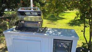 En portabel utomhusgrill med en yta i rostfritt stål, en inbyggd ugn och en papperskorg i närheten.