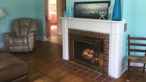 A living room with a fireplace, a recliner, and a television on a mantel. - Ocean view, FREE BEACH PASS. Short drive to multiple beaches and water park! (Fairhaven)