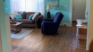 A living room with a brown sofa, a blue armchair, and a wooden coffee table. - Ocean view, FREE BEACH PASS. Short drive to multiple beaches and water park! (Fairhaven)