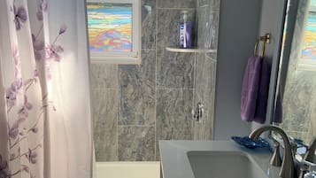 Een bad/douchecombinatie, een haardroger, handdoeken, toiletpapier