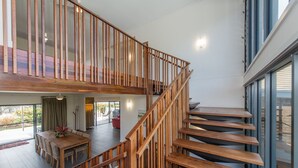 Een modern interieur met een houten trap, een eethoek en grote ramen.