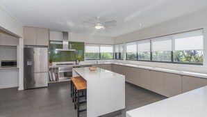Een moderne keuken met een centraal eiland, inbouwapparatuur en grote ramen.