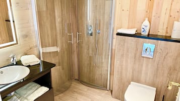 A modern bathroom with a wooden vanity, a sink, a toilet, and a shower enclosure.