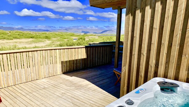 Una terraza de madera con un jacuzzi y vistas a montañas.