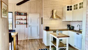 A compact kitchen with wooden cabinetry, a built-in stove, and a coffee maker.