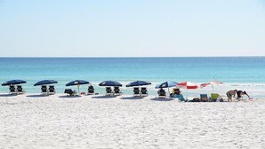 A beach with rows of beach chairs and umbrellas, a clear sky, and the ocean in the background. - BEACHSIDE 2 SANDESTIN SUMMER DISCOUNTS! BEACH FRONT 1 BR NEW POOL & HOT TUB! (Miramar Beach)