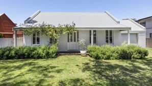 A single-story house with a white exterior, a grey roof, and a front porch. - Pet friendly Riverside Retreat (Barwon Heads)