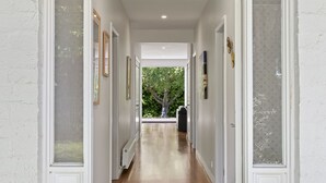 A hallway with wooden flooring, white walls, and framed pictures. - Pet friendly Riverside Retreat (Barwon Heads)