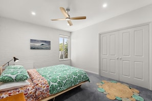 A bedroom with a bed, a ceiling fan, a window, and a door. - Pet friendly Riverside Retreat (Barwon Heads)